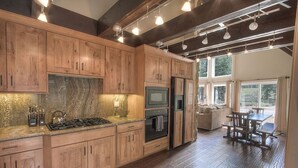 A modern kitchen with wooden cabinets, a granite countertop, and stainless steel appliances.