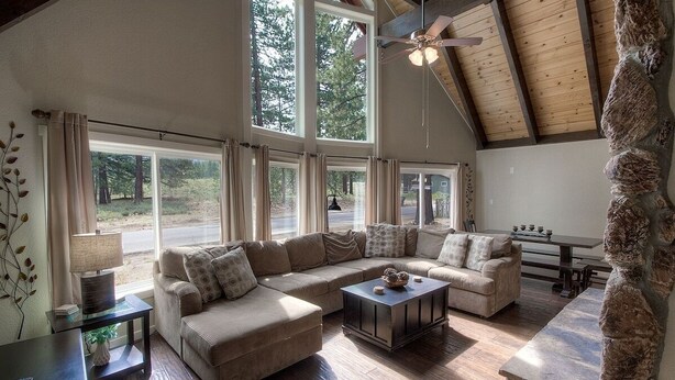 A spacious living room with a large sectional sofa, a coffee table, and a stone accent wall.