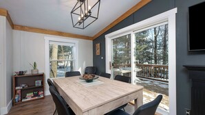 Un coin repas comprenant une table en bois, des chaises, une bibliothèque et un téléviseur.