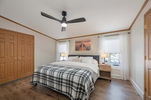 Una camera da letto con un letto, comodini, una ventola a soffitto e un'armadio in legno.