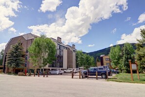 A modern building with a parking area, surrounded by trees and a mountain in the background. - Wh405 Wheeler House 3 Bedroom Condo by RedAwning (Copper Mountain)