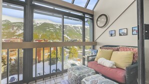 A room with a large skylight, a sofa with patterned cushions, a round wall clock, and framed pictures on the wall. - Wh405 Wheeler House 3 Bedroom Condo by RedAwning (Copper Mountain)