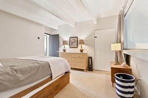 A bedroom with a bed, dresser, bedside lamps, a window, and a trash can. - Wh405 Wheeler House 3 Bedroom Condo by RedAwning (Copper Mountain)