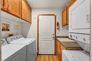 A compact laundry room with a washing machine, dryer, and a small sink. - Wolfpack Refuge 4 Bedroom Home by RedAwning (South Lake Tahoe)