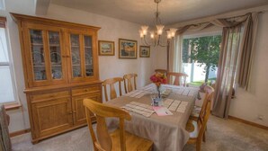 A dining room with a wooden cabinet, a chandelier, and a table set for four. - Wolfpack Refuge 4 Bedroom Home by RedAwning (South Lake Tahoe)