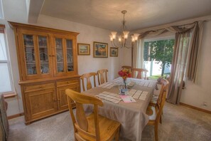 Ein Esszimmer mit einer Holzvitrine, einem Kronleuchter und einem Tisch für vier Personen.