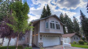 A two-story house with a garage, surrounded by trees and a well-maintained lawn. - Wolfpack Refuge 4 Bedroom Home by RedAwning (South Lake Tahoe)