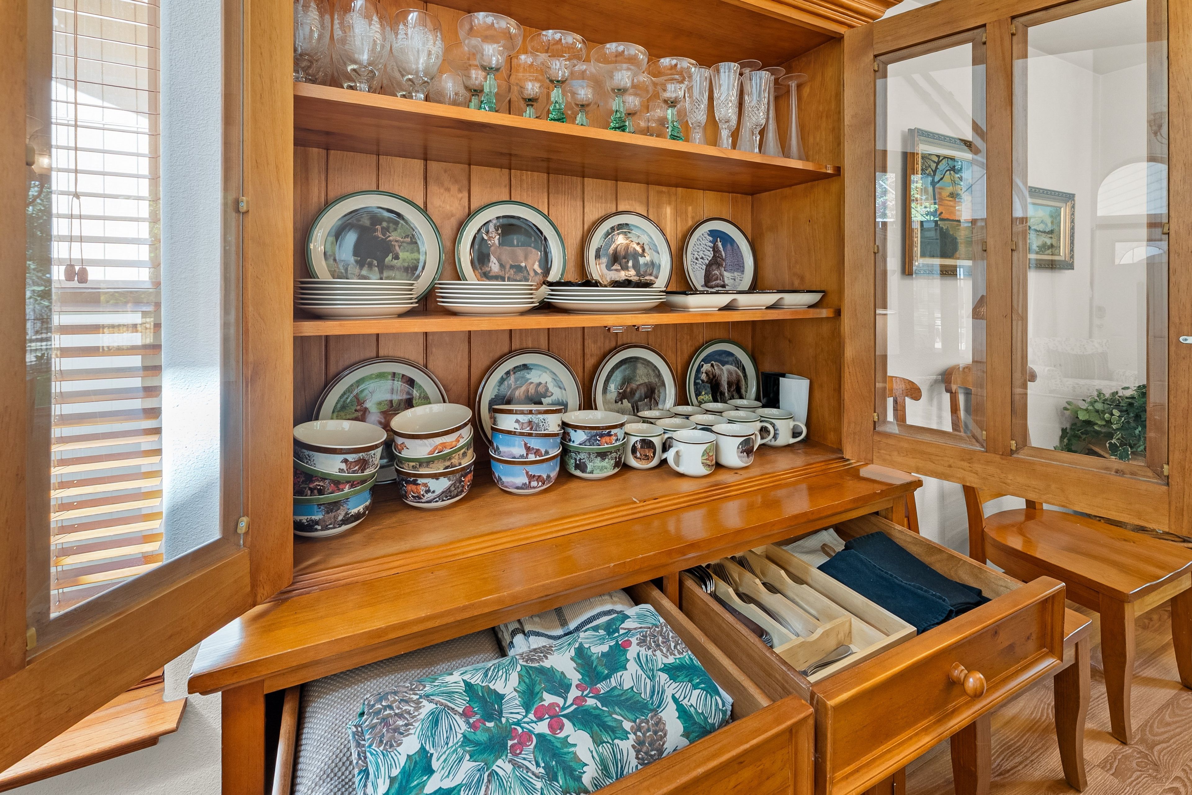 Un mueble de madera con cristalería, platos y cuencos.