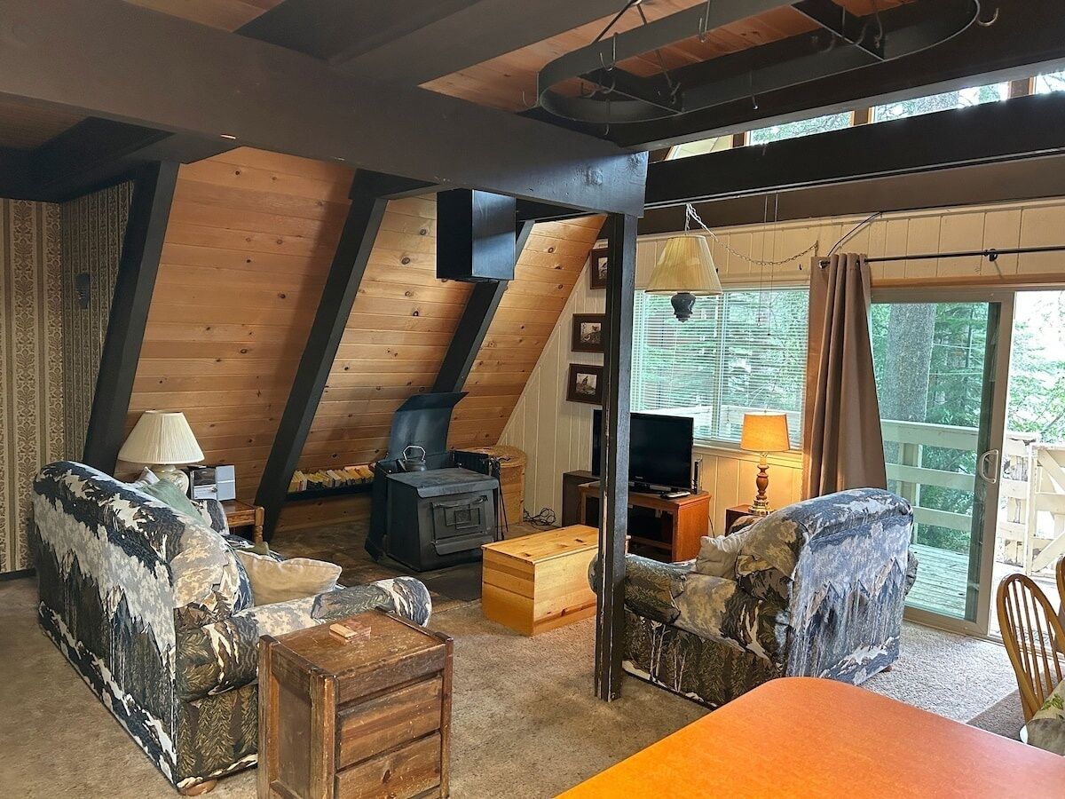 Ein gemütliches Loftsesselzimmer mit Kamin, Holzbalken und einem großen Fenster mit Blick auf eine Terrasse.