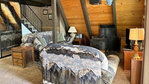 A cozy attic bedroom with a bed, a TV, and a fireplace. - Lodgepole Chalet 3 Bedroom Home by RedAwning (South Lake Tahoe)