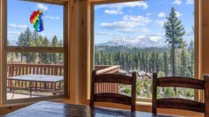 Una habitación con un ventanal grande con vistas a un bosque y montañas.