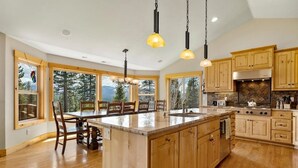 Una cocina amplia con armarios de madera, una isla grande y vistas al bosque.