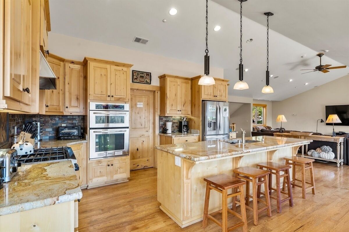 A spacious kitchen with wooden cabinets, stainless steel appliances, and a large island with stools.