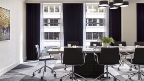 Une salle de conférence dotée d’une grande table, de chaises noires et d’un lustre.