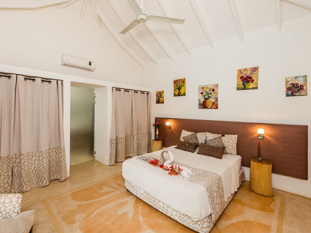 Une chambre à coucher avec un lit, des rideaux, une table de chevet et des œuvres d’art murales.