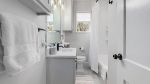 Un baño moderno con un lavabo blanco, espejo y toallero.