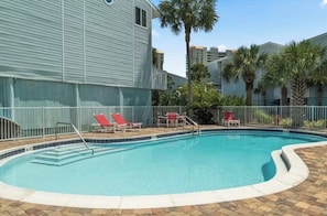 A swimming pool with steps leading into it, surrounded by a fence.