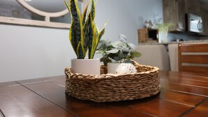 Una mesa de comedor con una cesta tejida que contiene plantas en macetas y un objeto decorativo.