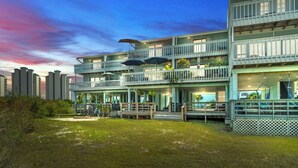Un hotel de varios pisos con balcones exteriores, una zona de piscina y vistas al horizonte de la ciudad.