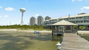 Un hotel frente a la playa con un muelle de madera, un pabellón y una torre de agua al fondo.