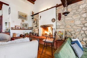 Un salon chaleureux avec une cheminée en pierre, des poutres apparentes et un coin salon confortable.