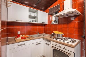 A kitchen with white cabinets, a wooden countertop, a gas stove, and a red-tiled backsplash. - Lovely Holiday Home By The Sea, Selce, Croatia (Selce)