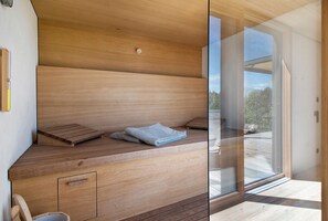 Una sauna de madera con bancos, una toalla y un vidrio que da a un espacio exterior.