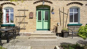 Un edificio de ladrillo con una puerta verde, dos ventanas y un letrero con el número 29.