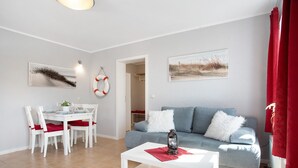 Una sala de estar con sofá, mesa de comedor, sillas y una mesa baja.