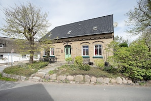 Un bâtiment à deux étages avec une porte verte, des marches en pierre et un mur en pierre.
