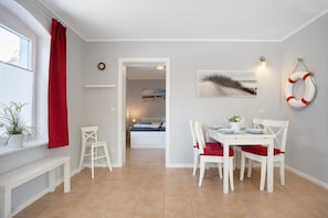 Un coin repas avec une table dressée pour quatre personnes, un banc et une chaise.
