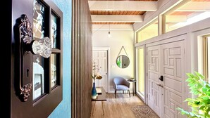 Een gang met een houten plafond, een blauwe muur en een deur met een spiegel.