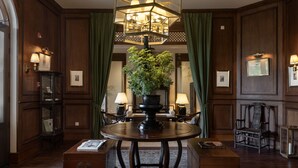 A formal dining room with a round table, green curtains, and a chandelier. - Sela  (Hang Dong)