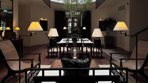 A spacious lobby with a high ceiling, a central table surrounded by chairs, and multiple lamps providing ample lighting. - Sela  (Hang Dong)
