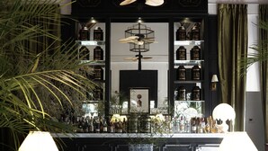 A bar area with a counter, shelves with bottles, a hanging fan, and two lamps. - Sela  (Hang Dong)