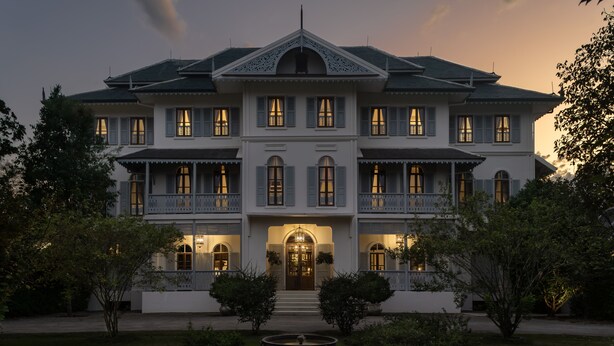 A large, two-story building with a symmetrical facade, multiple windows, and a central entrance with steps. - Sela  (Hang Dong)