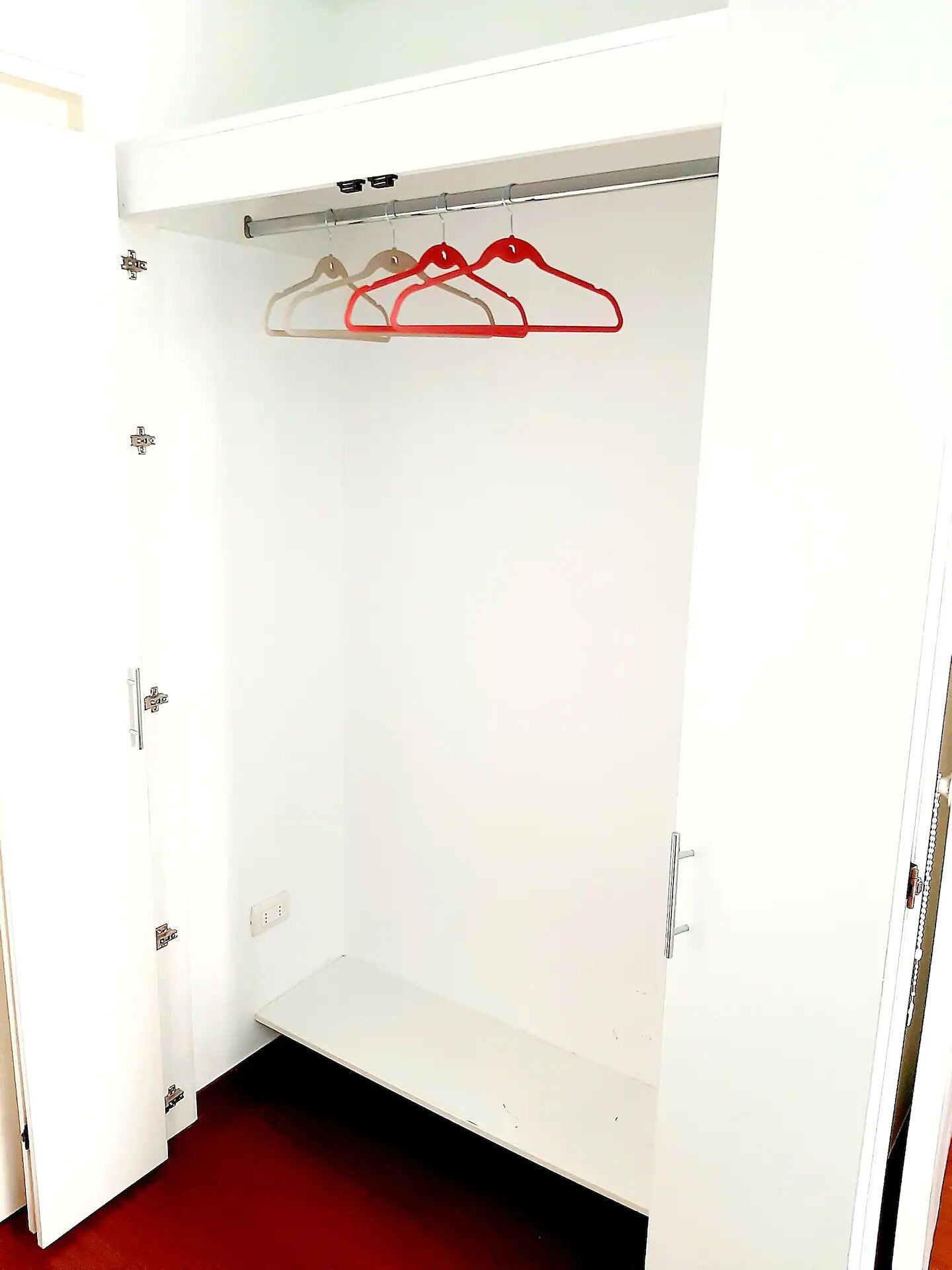 Une armoire blanche avec une tringle et une seule porte.