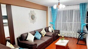 Ein Wohnzimmer mit braunem Ledersofa, einem Couchtisch und einer Kristallleuchter.