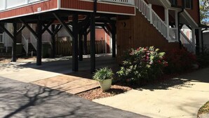 Een huis met twee verdiepingen, een overdekte veranda, een trap en een tuin met bloemen.