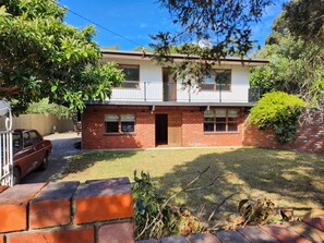 A two-story house with a brick facade, a front door, and a garage. - Large Retro Beach House with Style Class and Fun (Rye)