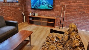 A living room with a brick wall, a flat-screen TV, a sofa, a coffee table, and a TV stand.