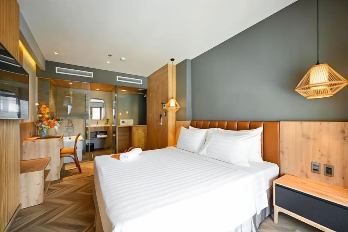 Une chambre d’hôtel avec un grand lit, un bureau, une chaise et un miroir.