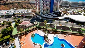 A hotel with a large pool, multiple floors, and a view of the ocean.