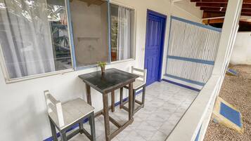A small room with a table and two chairs, a window with a curtain, and a blue door.
