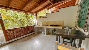 A kitchen with a tiled floor, a wooden counter, and a window overlooking greenery. - Hotel Exotic Lodge (Cahuita)