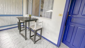 A room with a blue door, a window with curtains, a table with chairs, and a potted plant. - Hotel Exotic Lodge (Cahuita)