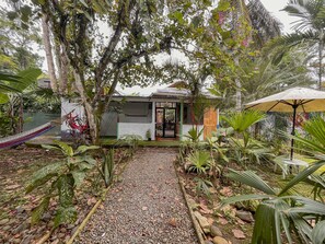 Une maison entourée d’une végétation luxuriante, un hamac et un petit jardin.