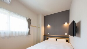 Quarto de hotel com cama, janela com cortinas, televisão na parede e interruptor de luz.