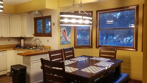 Una cocina con armarios blancos, una encimera de madera, un fregadero y una mesa de comedor con sillas.