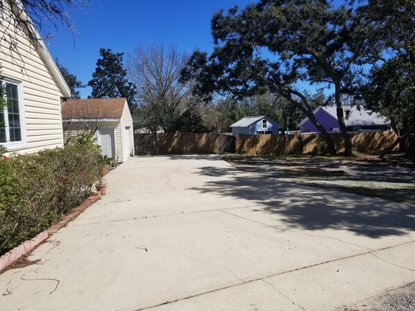 Un camino de acceso residencial con garaje, cerca de madera y un árbol.